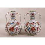 A pair of Chinese polychrome porcelain garlic head shaped vases with two handles, decorated with