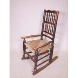 A C19th oak Lancashire spindle back rocking chair with a rush seat, 36½" high