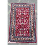 A red ground full pile Persian village rug with all over floral decoration to the central field, 50"