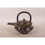 A Japanese redware pottery teapot possibly by Kozan, with cursive blue and cream foliate decoration,