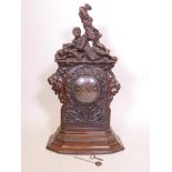 A C19th Black Forest walnut bracket clock, with carved decoration of oak and acorns under a figure