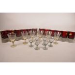Two sets of six Luminarc ruby glass wine glasses on clear stubby stems and feet, together with a set