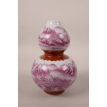 A Chinese double gourd porcelain vase decorated in pink enamels depicting a riverside landscape,