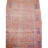 An Oriental hand woven wool rug with geometric patterns on a faded red field, 43" x 65"
