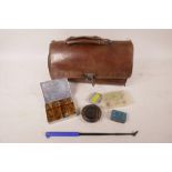A leather bag containing various vintage fishing equipment including fly box and flies, 11" long