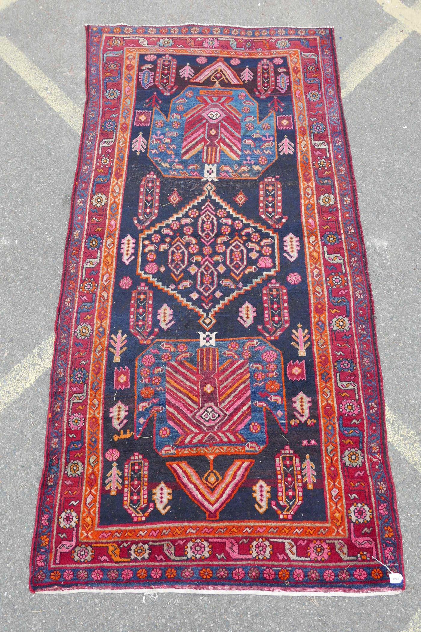 A red and blue ground Persian wool runner decorated with stylised birds and medallions, 46½" x 98"