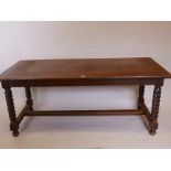 A C19th French oak refectory table, with pull out bread board, raised on twisted supports united