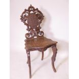 A C19th Black Forest musical chair with carved and pierced back, raised on cabriole supports