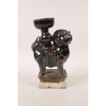 A Chinese black glazed pottery candlestick in the form of a fo dog, 7" high