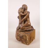 A pottery sculpture of a lovers' embrace, on a wood plinth, 13½" high