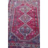 A Persian red ground carpet with geometric pattern, edges frayed, 71" x 93"