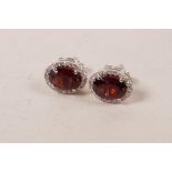 A pair of 18ct white gold, garnet and diamond cluster earrings, approximately 2.2cts