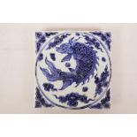 A Chinese blue and white porcelain tile decorated with a mythical carp, 8" x 8"