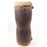 A double end tribal drum with carved wooden body and hide heads, 18½" long