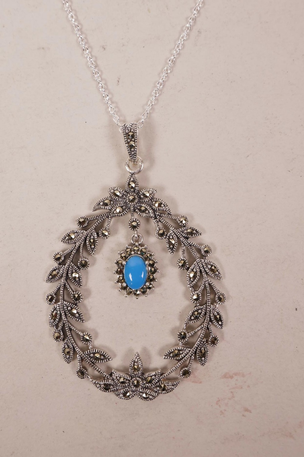 A 925 silver and marcasite set pendant necklace in the form of a wreath with a turquoise drop, 3"