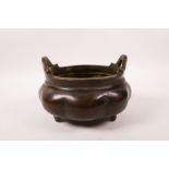 A Chinese bronze two handled censer of lobed form on tripod feet, impressed 6 character mark to
