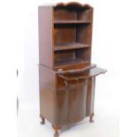 A 1930s mahogany serpentine fronted dwarf bookcase with open shelves and brushing slide, raised on