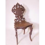 A C19th Black Forest musical chair with carved and pierced back, raised on cabriole supports