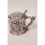 A Dutch style silver mustard pot and cover with pierced and engraved decoration of figures and