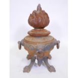 A C19th cast iron urn with four ring handles, raised on paw feet, the cover cast as a flame, 29"