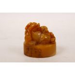 A Chinese amber soapstone seal with carved kylin decoration, character inscription to side, 2" x 1½"