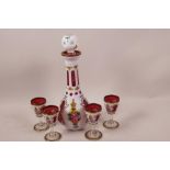 A Bohemian cased red and white glass liqueur set of decanter and four glasses, with floral painted