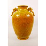 A Chinese ochre ground pottery two handled vase with raised decoration of temple dogs, 4 character