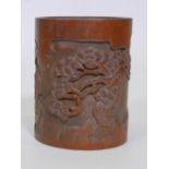 A Chinese bamboo brush pot with carved decoration depicting figures under a cypress tree, 7" high