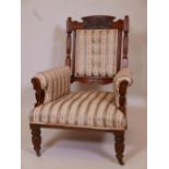 A Victorian walnut show frame armchair with a carved crest, raised on reeded supports, 38½" high