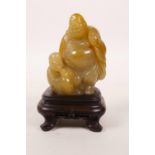 A Chinese soapstone carving of Buddha and his attendant, on a hardwood stand, 4" high