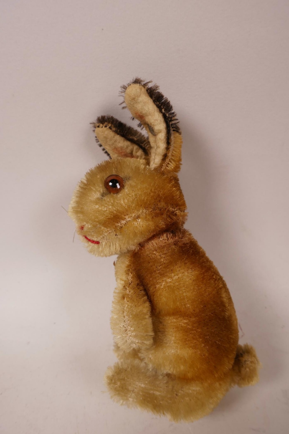 A 1952/53 Steiff begging rabbit, golden mohair, fixed limbs, brown and black glass eyes, red