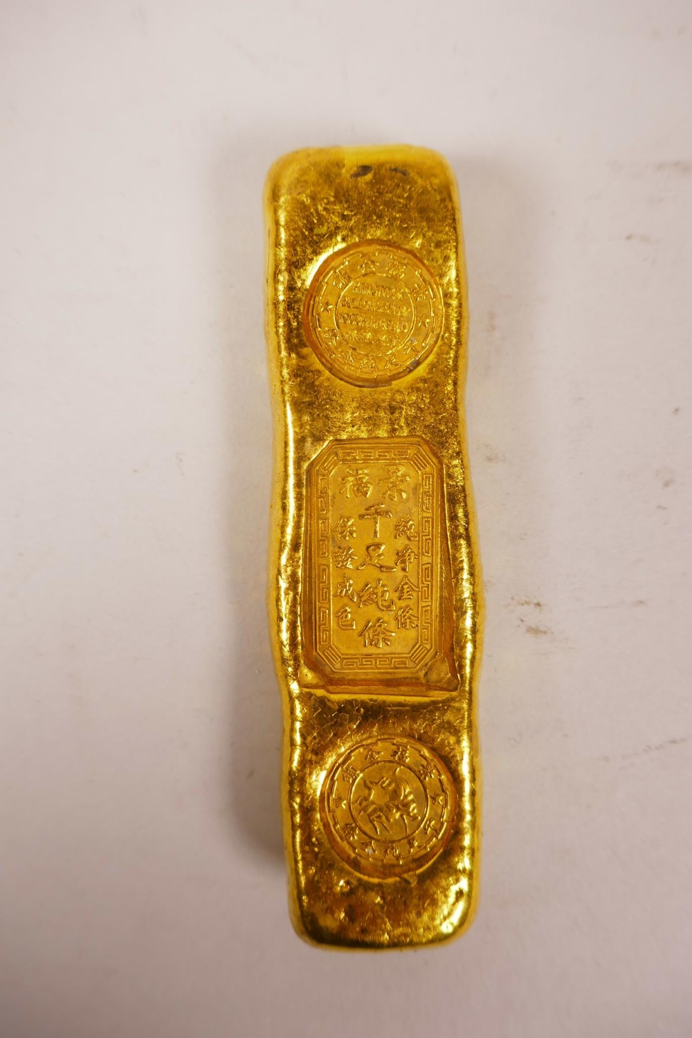 A Chinese gilt white metal trade token/ingot, 4" long, 190 grams