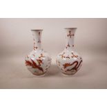 A pair of Chinese porcelain vases with red and gilt decoration of dragons and phoenix chasing the