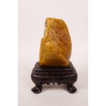 A Chinese soapstone carving of figures in a landscape, on a hardwood stand, 4" high