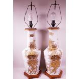 A pair of Oriental porcelain table lamps decorated with gold coloured flowers on a white ground,