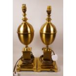 A pair of heavy brass table lamps in the shape of baluster urns, on square section plinths, 19" high