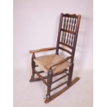 A C19th oak Lancashire spindle back rocking chair with a rush seat, 36½" high
