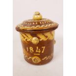 A C19th slipware tobacco jar decorated with patterns in yellow slip on a brown ground, bears the