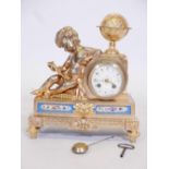 An ormolu mantel clock, with cherub reading by a globe, the base with inset Sevres style porcelain