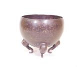 An Oriental bronze bowl with spattered patination, raised on elephant mask supports, 9½" high