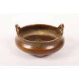 A small Chinese bronze censer with two phoenix eye handles on tripod supports, impressed seal mark