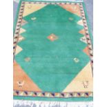 An Indian hand woven deep pile wool carpet with stylised bird decoration on a green field, 72" x 49"