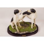 A composition figure of two greyhounds on an oval wooden plinth, 8½" high