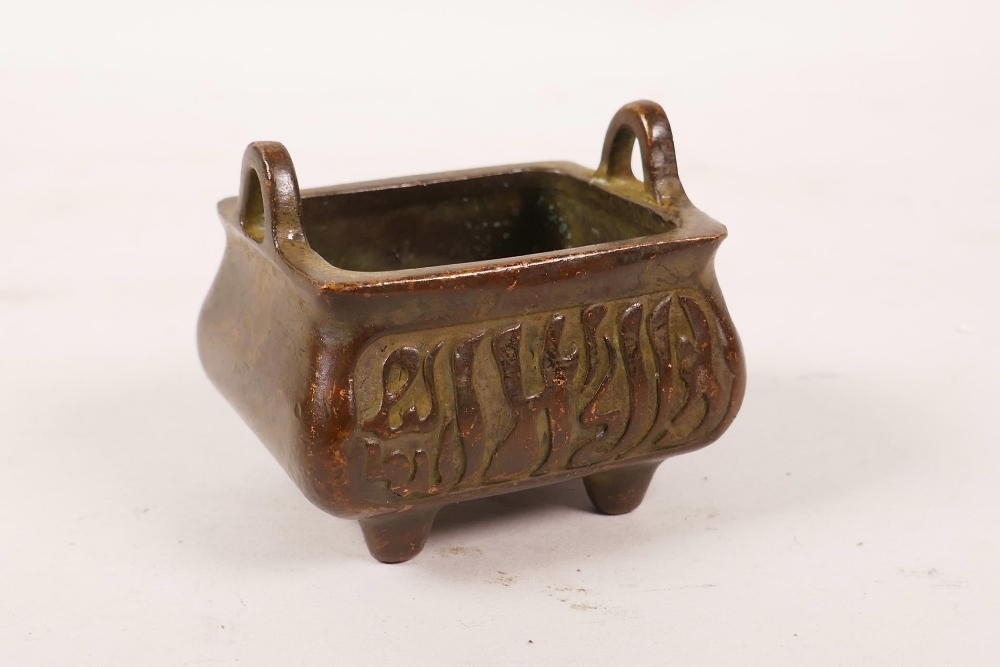 A Chinese bronzed metal censer with two handles and calligraphy decoration, character mark to