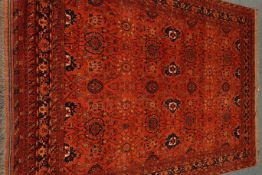 Persian Bokhara red ground rug, repeating floral border,