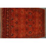 Persian Bokhara red ground rug, repeating floral border,