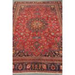 Persian Meshed red ground rug, repeating floral border, central medallion,