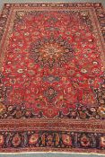 Persian Meshed red ground rug, repeating floral border, central medallion,