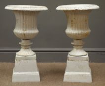 Pair classical style antique finish garden urns on stepped plinths,