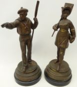 Pair patinated spelter figures of a sailor and fisher girl on ebonised circular plinths,